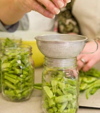 Photo of someone filling jars with green beans.