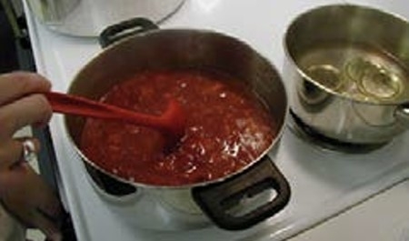 someone stirring a pot on s stove.