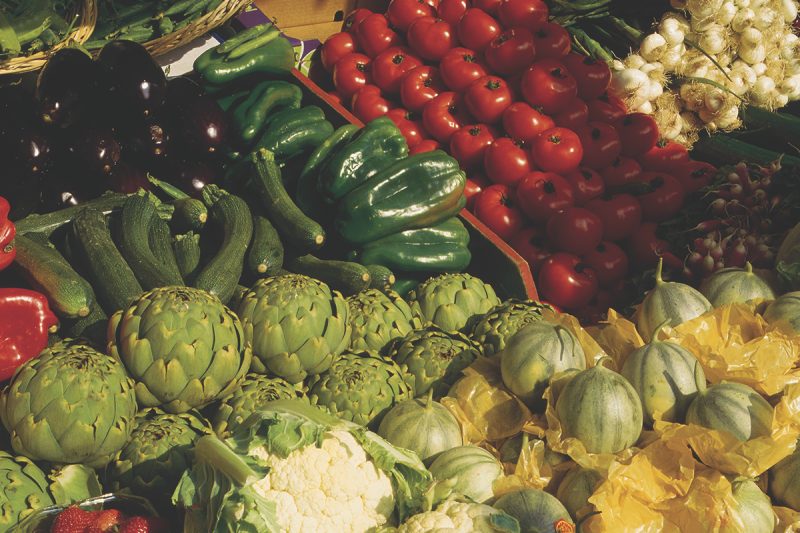 A photograph of a variety of vegetables, including zuchini, artichoke, eggplant, peppers, tomatoes, and watermelon.