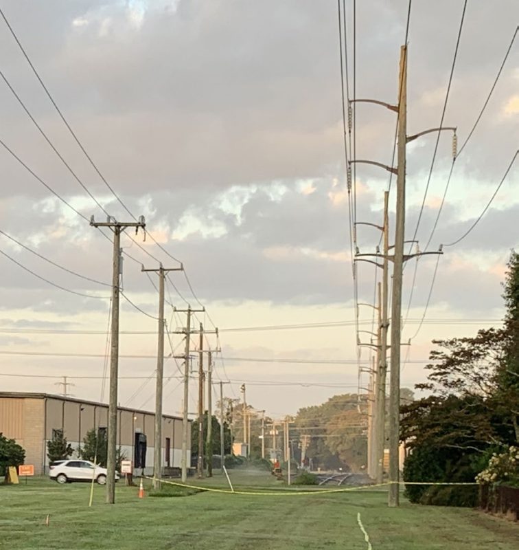 The photo shows two rows of utility poles and lines. The poles to the left are shorter and holds fewer lines, while the poles to the right are taller and hold more lines.