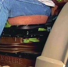 A person sitting on an orange tractor seat.