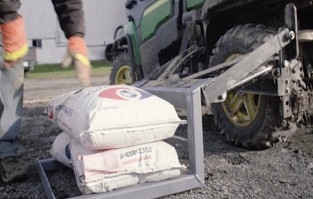 A large sack for farming on a lift connected to a utility vehicle