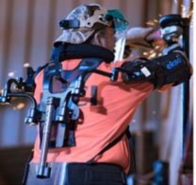A person using an angle grinder on a piece of metal while wearing an exoskelton