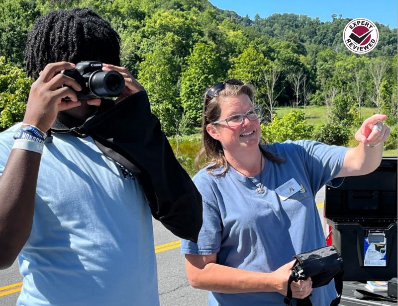 A volunteer points ahead while a student aims a camera