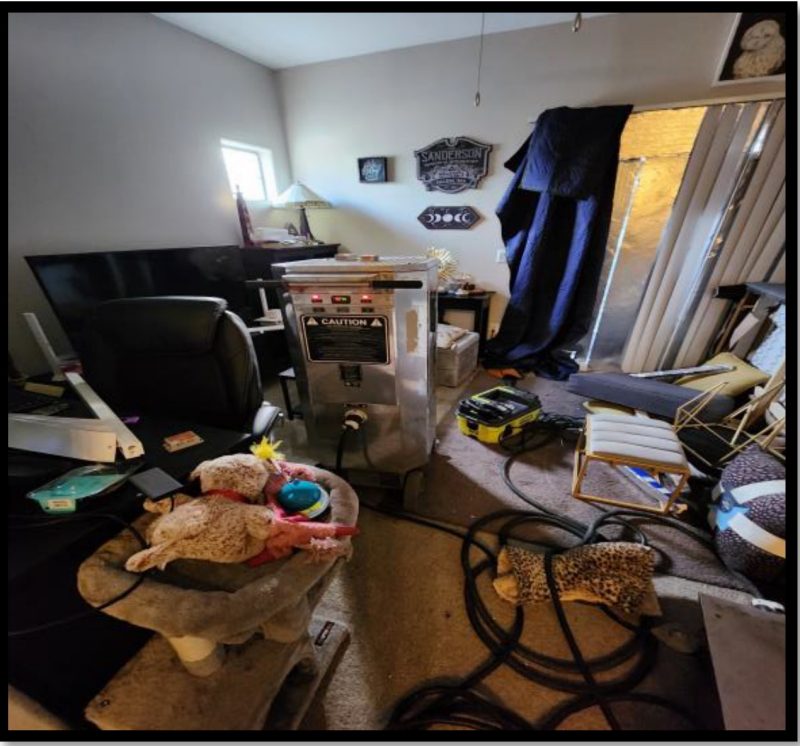 An electric bed bug heater placed in the center of a cluttered living room.