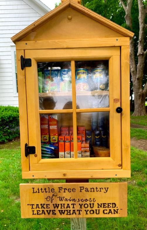 Donating Food Through a Share Pantry A share pantry, made of wood with a framed door on the front. There are two shelves inside, filled with nonperishable foods. There is a sign on the bottom of the pantry saying "Little Free Pantry of Wainscott. 'TAKE WHAT YOU NEED, LEAVE WHAT YOU CAN."