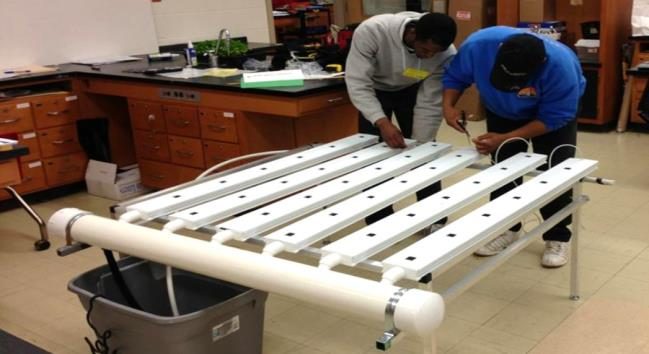 Figure 2. Two men constructing a small NFT system inside a lab.